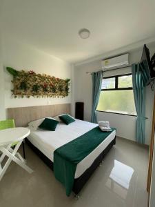 a bedroom with a bed and a table and a window at Hotel Primavera Santa Fe in Santa Fe de Antioquia