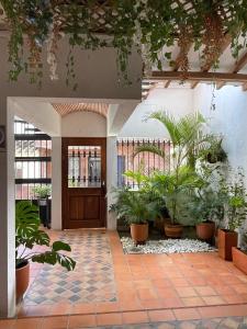 Hotel Primavera Santa Fe في سانتا في دي أنتيوكيا: لوبي فيه نباتات الفخار وباب خشبي