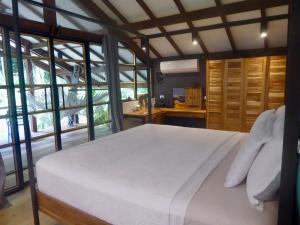 a bedroom with a large white bed and windows at Uvita Bali Bosque Retreat in Uvita