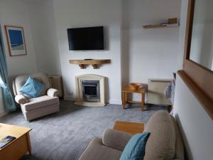 a living room with a fireplace and a tv on the wall at Cuddys Corner in Beadnell