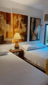 two beds in a room with paintings on the walls at Ateliê 22 in Natal