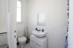 een witte badkamer met een toilet en een wastafel bij Studio cosy en centre-ville Proche de Paris in Pierrefitte-sur-Seine