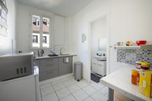 eine weiße Küche mit einer Spüle und einer Theke in der Unterkunft Studio cosy en centre-ville Proche de Paris in Pierrefitte-sur-Seine