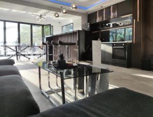 a living room with a glass table and a kitchen at Casa Palmera in Novi Sad