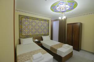 Una habitación de hotel con dos camas y una lámpara de araña. en Sahar Boutique Hotel, en Bukhara