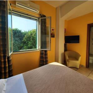 a bedroom with a bed and a window and a chair at Hotel Sirio in Reggio di Calabria