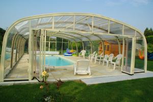 un pavillon en verre avec des chaises et une piscine dans l'établissement La Grimodière Chambre en rez de chaussée, à Ranville