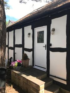 a black and white shed with a white door at Round-y-Corner in Macclesfield