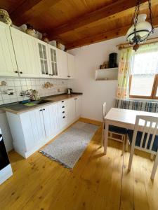 a kitchen with white cabinets and a dining table at Chata Monika in Frymburk