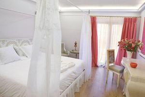 a bedroom with a white bed and a table and a desk at Hotel Sa Calma in Begur