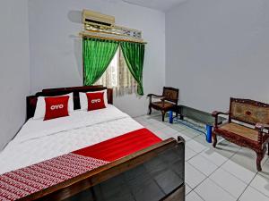 a bedroom with a bed with red pillows and a window at SPOT ON 91372 Wisma Bulin in Purwokerto