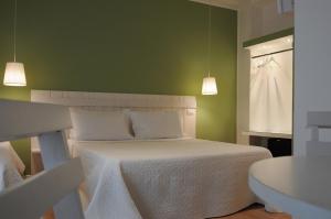 1 dormitorio con cama blanca y pared verde en B&B Medinblu, en Reggio Calabria
