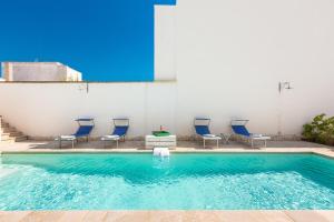 a swimming pool with blue chairs and a table at Dimora Blu by BarbarHouse in Cerfignano