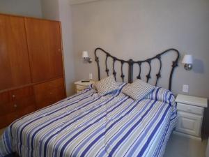 1 dormitorio con 1 cama con sábanas de rayas azules y blancas en Departamento Huarpes en Villa Gesell