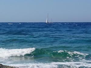 un barco en el océano con un velero a lo lejos en ~~ Sea Breeze covered house ~~, en Mókhlos
