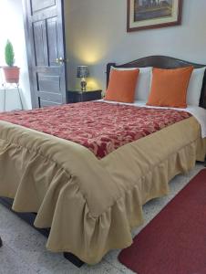 1 dormitorio con 1 cama grande con almohadas de color naranja en Hostal Flores, en Quito