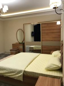 um quarto com uma cama grande e um espelho grande em Huvaydo Residence Apartment em Tashkent