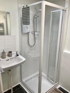 a white bathroom with a shower and a sink at Briscoe Lodge Self Catering Apartments in Windermere