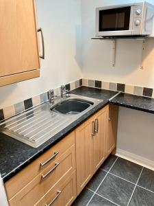 a kitchen with a sink and a microwave at Briscoe Lodge Self Catering Apartments in Windermere