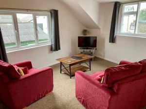 ウィンダミアにあるBriscoe Lodge Self Catering Apartmentsのリビングルーム(赤い椅子2脚、テレビ付)