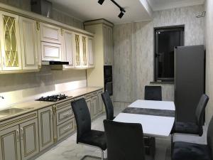 uma cozinha com uma mesa branca e cadeiras em Huvaydo Residence Apartment em Tashkent