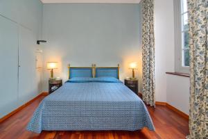 a bedroom with a blue bed with two lamps at Hotel Villa La Principessa in Lucca