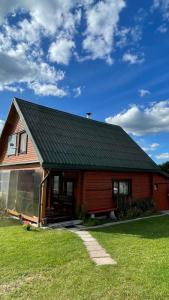 a house with a green roof and a grass yard at Saulėtekio 12 in Ignalina