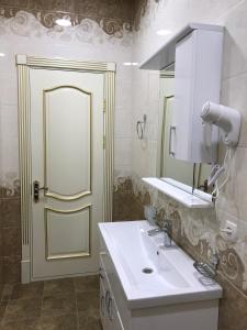 uma casa de banho com um lavatório, um espelho e uma porta em Huvaydo Residence Apartment em Tashkent