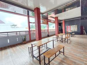 a room with tables and benches and large windows at Hotel New Dieng By Helocus in Berastagi