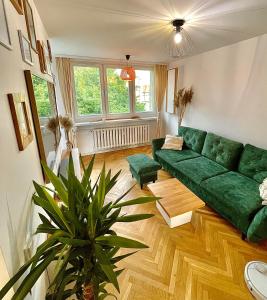 a living room with a green couch and a plant at Luxurious BOHO style apartm. *HOME OFFICE* +Desk in Katowice