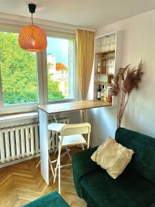 a living room with a table and a green couch at Luxurious BOHO style apartm. *HOME OFFICE* +Desk in Katowice