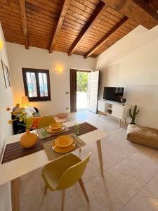 sala de estar con mesa, sillas y TV en SURFING COTTAGES en Gizzeria