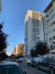 a parking lot with cars parked in front of a tall building at Apartemento tres Norte in Viña del Mar +7 photos