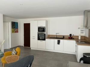 a kitchen with white cabinets and a yellow chair at Le Pélican Magnifique F2 in Ajaccio