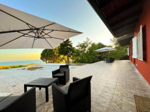 um pátio com uma mesa, cadeiras e um guarda-sol em SURFING COTTAGES em Gizzeria