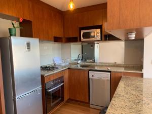a kitchen with stainless steel appliances and wooden cabinets at Apartemento tres Norte in Viña del Mar