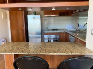 a kitchen with a granite counter top and a refrigerator at Apartemento tres Norte in Viña del Mar