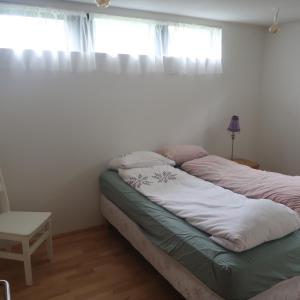 a unmade bed in a room with two windows at Large apartment close to the centre in Reykjavík
