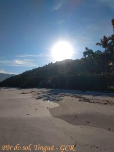 a sandy beach with the sun in the background at CASA DA ANA E ZÉ in Governador Celso Ramos