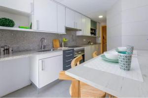 una cocina con armarios blancos y una mesa con sillas. en 4 rooms apartment in Tarragona, en Tarragona