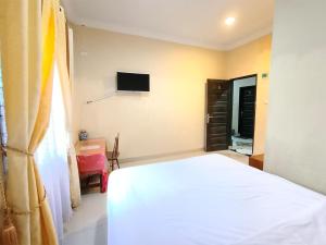 a bedroom with a white bed and a television at Hotel New Dieng By Helocus in Berastagi