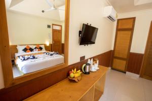 een slaapkamer met een bed en een grote spiegel bij Coral Beach Maldives in Hangnaameedhoo
