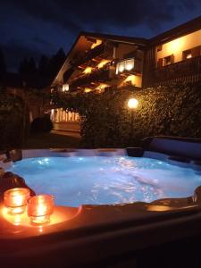 una vasca idromassaggio notturna con candele di Park Hotel Arnica a Falcade