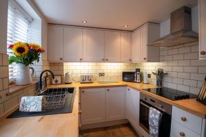 a kitchen with white cabinets and a sink at Apple Tree Cottage - Cosy 2 Bed with Deluxe HOT TUB & Log Burner in Hereford