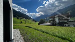 a view of a house with a green field and mountains at Studio11 in Neustift im Stubaital