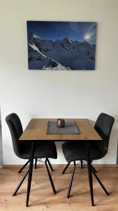 a dining room table with two chairs and a snow covered mountain at Studio11 in Neustift im Stubaital
