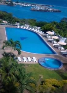 a large swimming pool with lounge chairs and the ocean at Apartamento con vista al mar in Catia La Mar