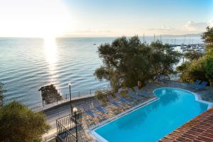 a swimming pool with chairs and the ocean in the background at Dimitra Studios in Benitses