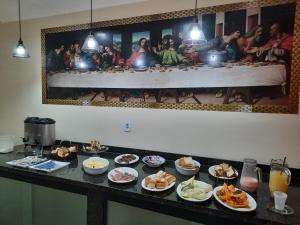 a buffet with plates of food on a table at Pousada Mãe Ternura Palace in Aparecida