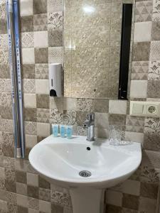 ein Badezimmer mit einem weißen Waschbecken und einem Spiegel in der Unterkunft Villa Story Hotel in Shekhvetili
